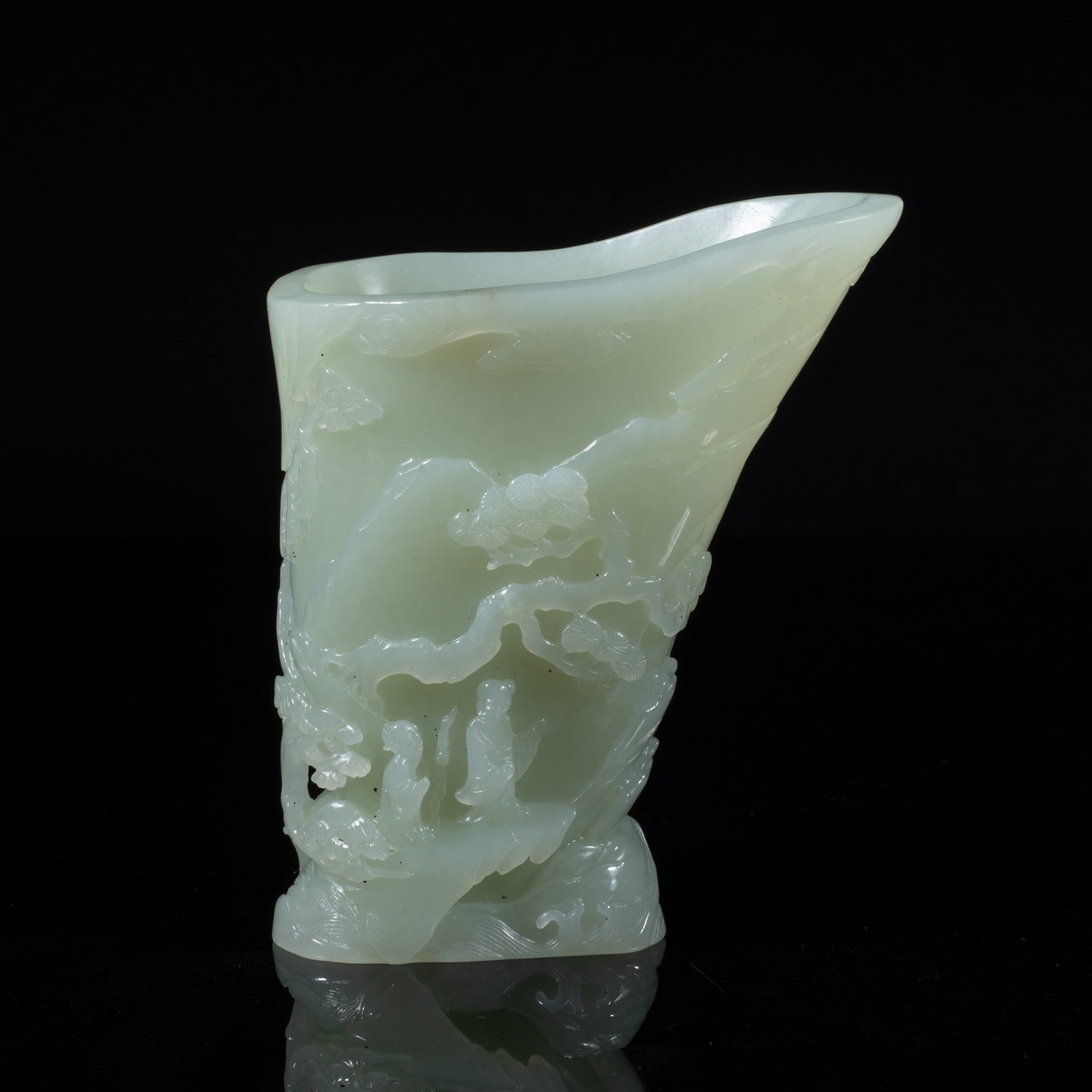 Chinese Jade Carved Libation Cup: The tapering cup finely carved with a scholar and his attendant standing by a river bank under a gnarled pine trees, all within a mountainous landscape amidst wutong and pine trees growing over the