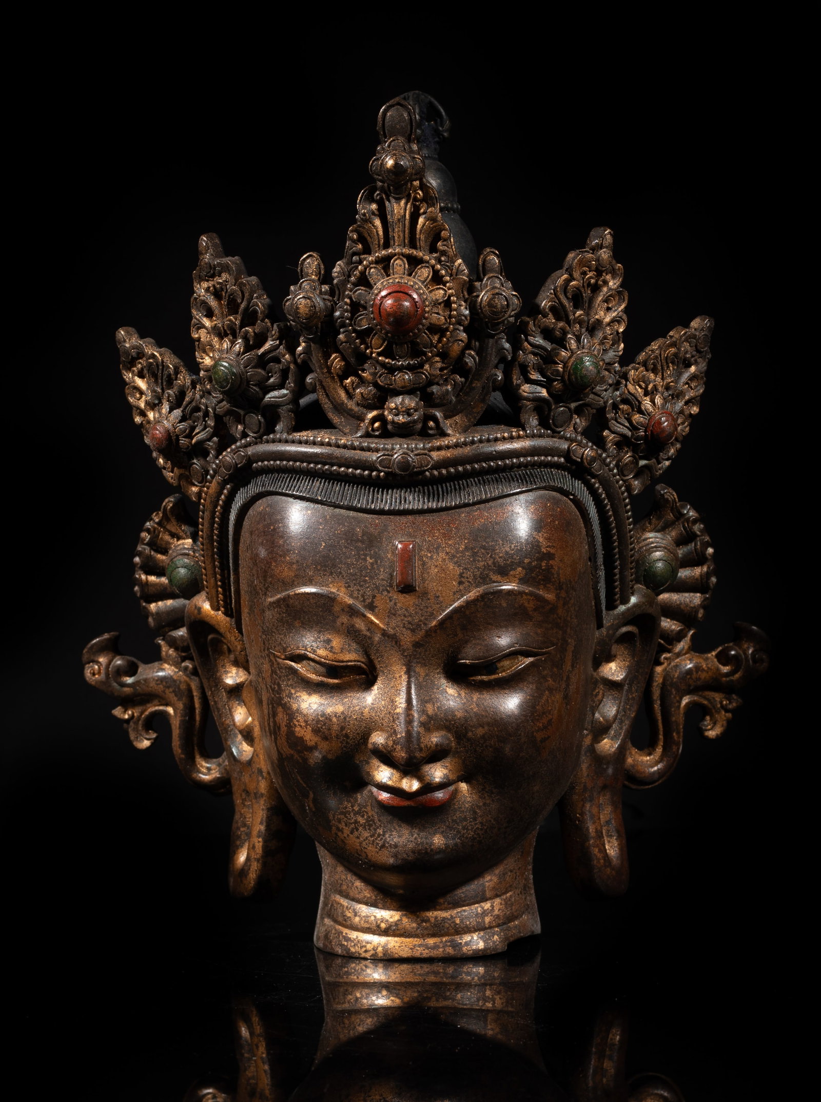 Chinese Gilt Bronze Sculpture of Buddha Head: Chinese gilt bronze buddha head, depicting an elaborate multi-peaked crown inlaid with gemstone, the serene face with downcast eyes, and a centered urna on the forehead. Approx. 9.7*8*5.5 inch. The Es