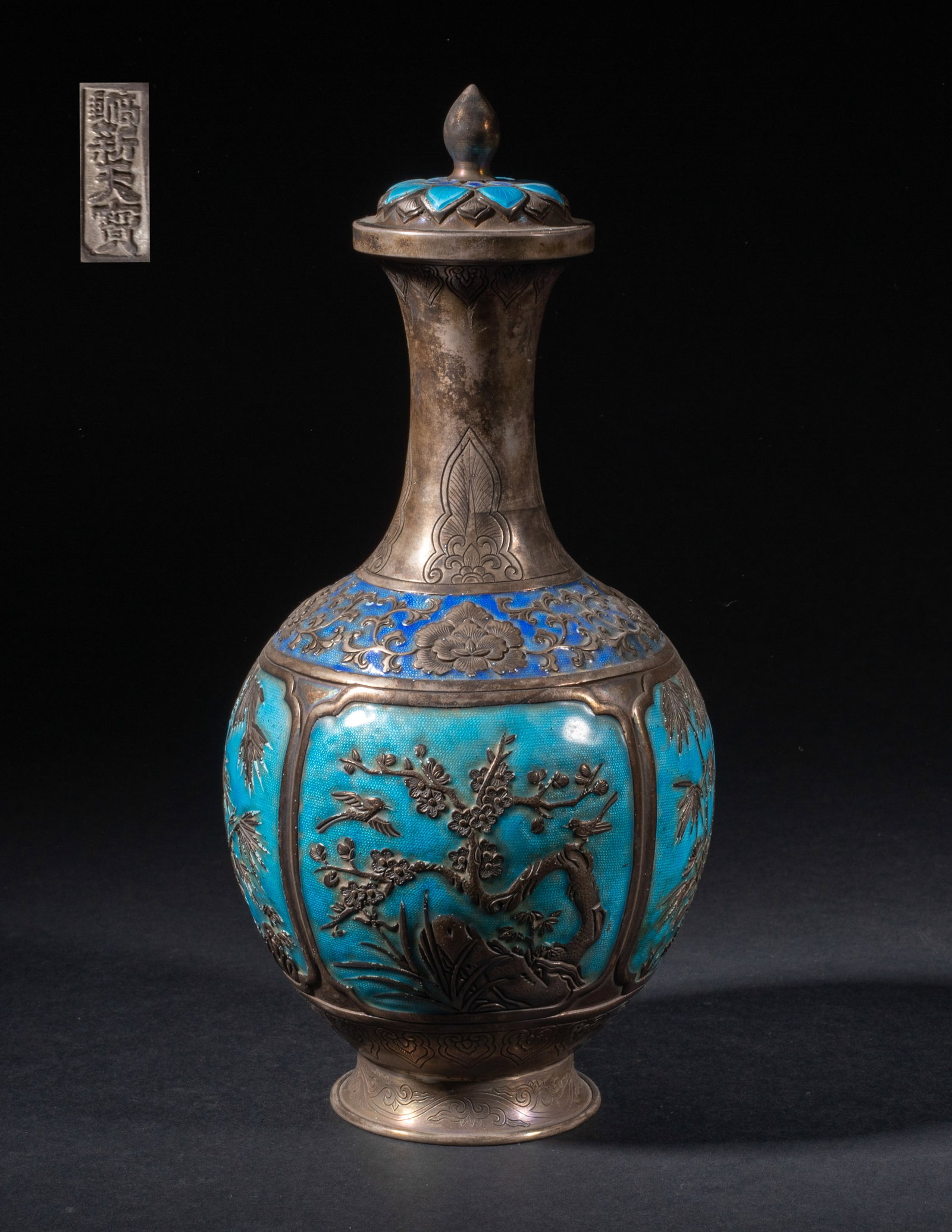 Chinese Enameled on Silver Vase: The globular body rising from a splayed foot to a slender waisted neck, the body enameled and carved with four panels enclosing plum blossoms, bamboo, chrysanthemum and orchid, the neck with flowers a
