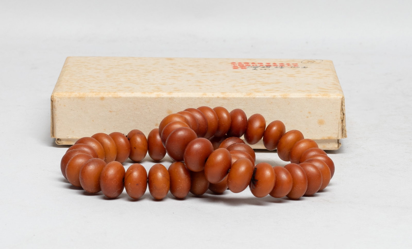 Two Chinese Export Amber Prayer Beads: Two strings of Chinese amber carved prayer beads, with box. Approx. 60 gram (total bead weight), The Estate of the E Los Angeles, 2023.
