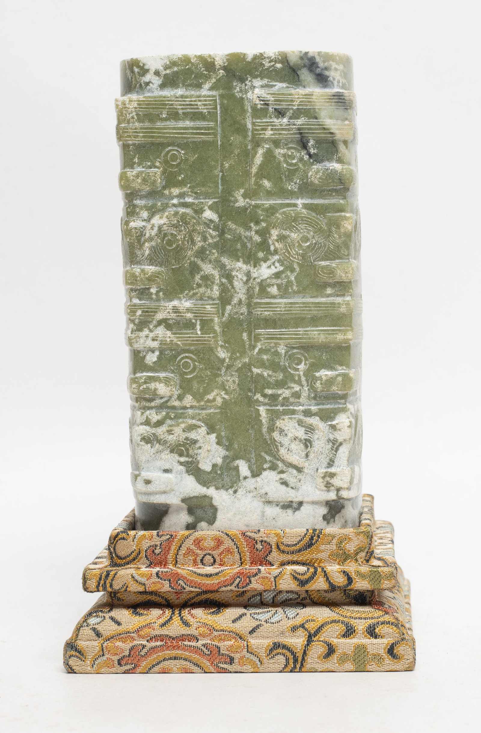 Chinese Jade/ Stone Carved Sculpture of Cong: Chinese jade/stone carved sculpture of cong, in the form of rectangular, with circular inner tube, divided vertically into four horizontal section, applied overall in greenish tone, with a stand. Appr