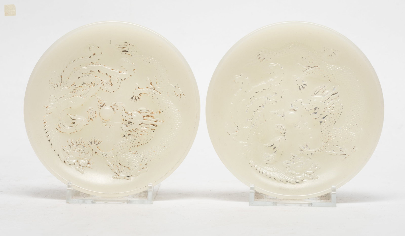 Two Chinese White Jade Like Glass Dishes: Two Chinese white jade-like glass dishes carved with dragon and phoenix, seal mark to the underside. Approx. 4.1 inch D (each).