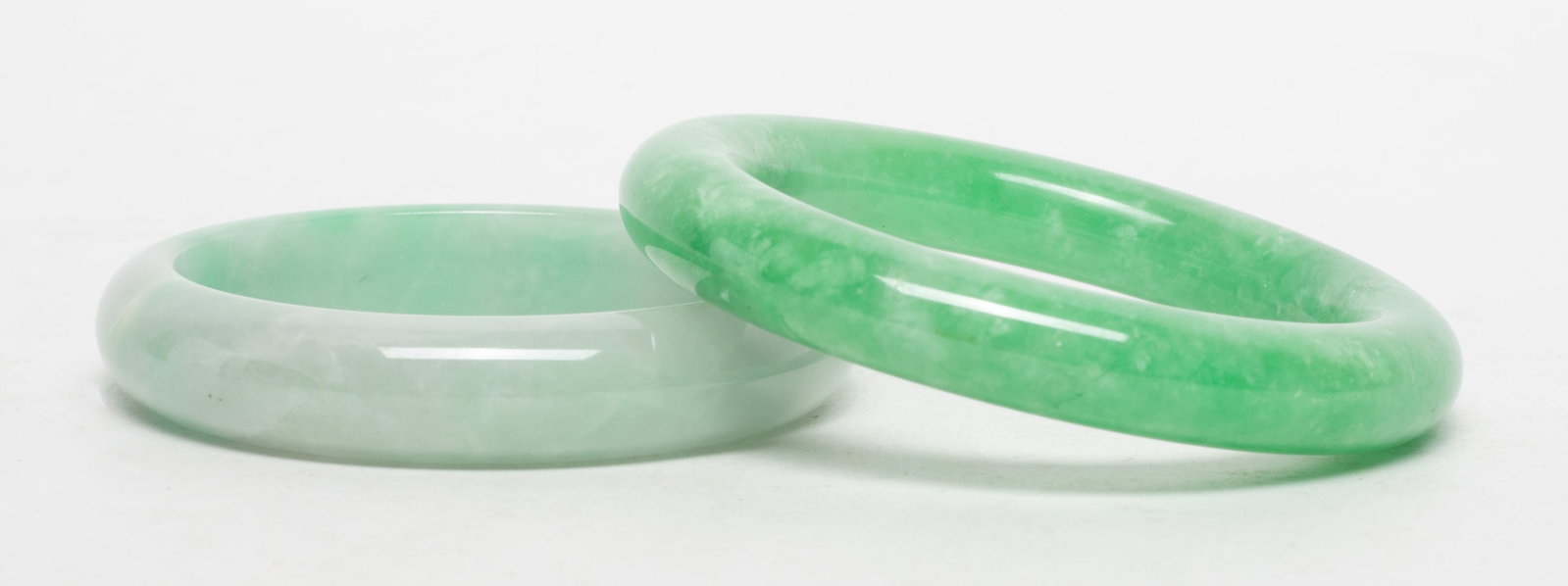 Two Chinese Export Jade Bangles: Two Chinese colored jade bangles. Approx. 3.3 inch outer diameter, 2.3 inch inner diameter (larger).