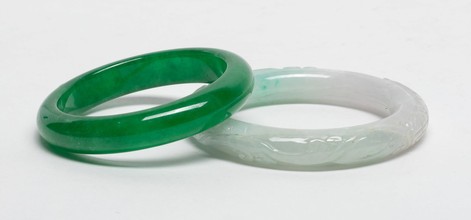 Two Chinese Colored Stone Bangles: Two Chinese colored stone bangles, one carved with mythical beast. Approx. 2.29 inch inner diameter (larger); 3.24 inch outer diameter (larger)