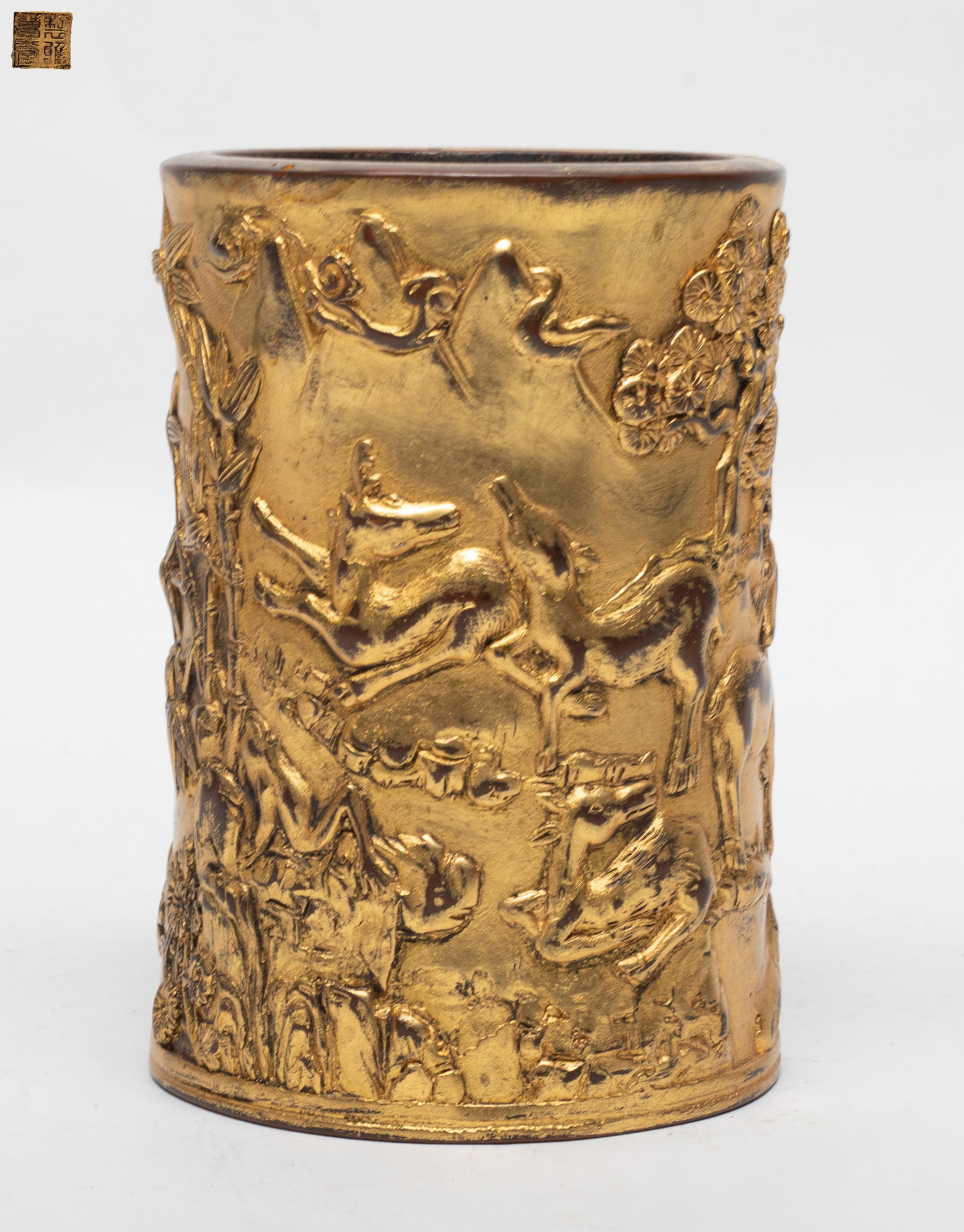 Heavy Chinese Gilt Bronze Brush Pot: Heavy Chinese gilt bronze brush pot, of cylindrical form, carved in high relief of the landscape scene detailed with bamboo stems and mountain, the base inscribed with a seal mark. Approx. 3.2*5.0