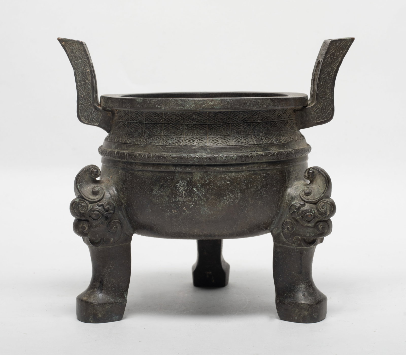 Chinese Export Bronze Censer: The compressed globular body with shallow rounded sides, set with a pair of upright handles and three bulging cabriole feet, the exterior decorated with geometrical and archaic patterns. Approx. 6.2*5
