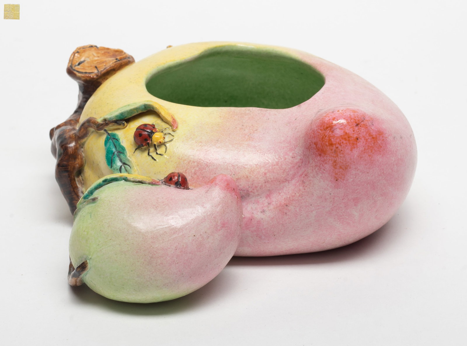 Chinese Famille Rose Porcelain Brush Washer: The body carved in shallow peach form borne on a high relief leafy fruiting gnarled branch forming the handle, the base inscribed a seal mark. Approx. 7.1*2.3 inch
