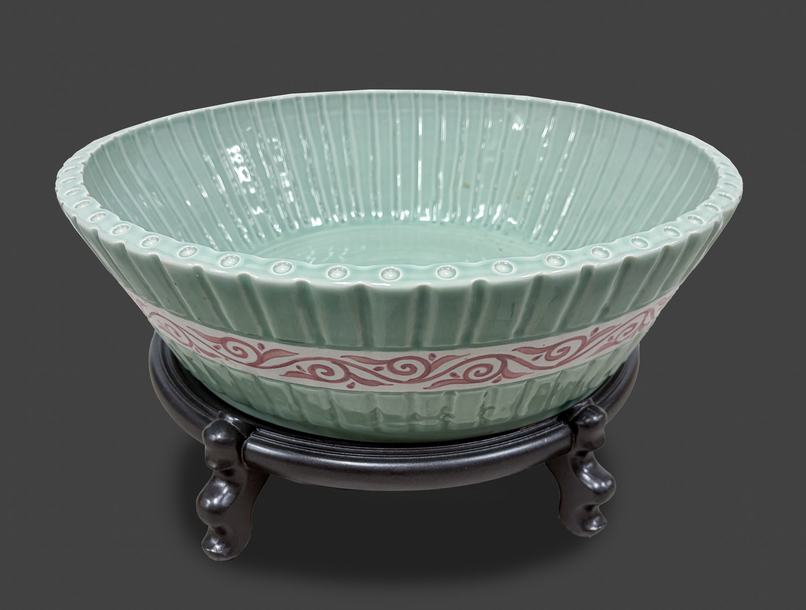 Massive Chinese Export Porcelain Bowl: The bowl sides carved with vertical bands, decorated with a border of copper-red scrolls at the centre, overall save for the unglazed base with celadon glaze, with a wood stand. Approx. 20.5*6 inch (w
