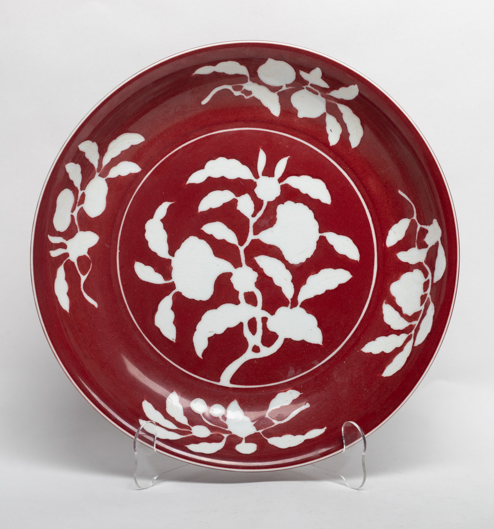 Large Chinese Export Porcelain Charger: Large Chinese export porcelain charger, detailed with white botanical and fruit motifs against a rich red background glaze, the exterior with a six-character mark. Approx. 12.8*2.1 inch