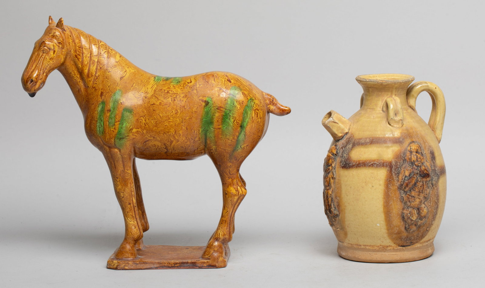 Estate Two Chinese Glazed Pottery Pieces: Including a standing horse sculpture, applied with yellow, brown and green glaze, and a pot of ovoid form, carved in raised relief with figures. Approx. 8.4*9*2.8 inch (horse size).