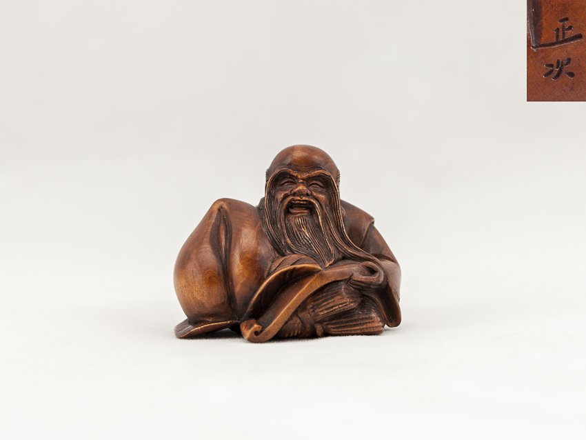 Antique Carved Box Wood Netsuke:Shou Lao: Finely carved antique box wood netsuke; of a seated and smiling Shou Lao holding a giant peach, signed. 4cm high