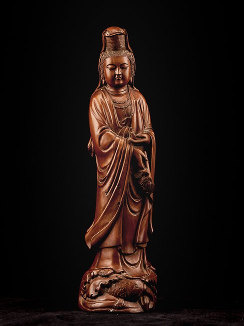 Chinese Antique Carved Box Wood Figure of Kuanyin: Standing elegantly on the stand modelled in the form of sea wave, Kuanyin's right hand holds a scroll with downcast eyes in serene expression and dressed in loose and long robe exposing the adorned ne