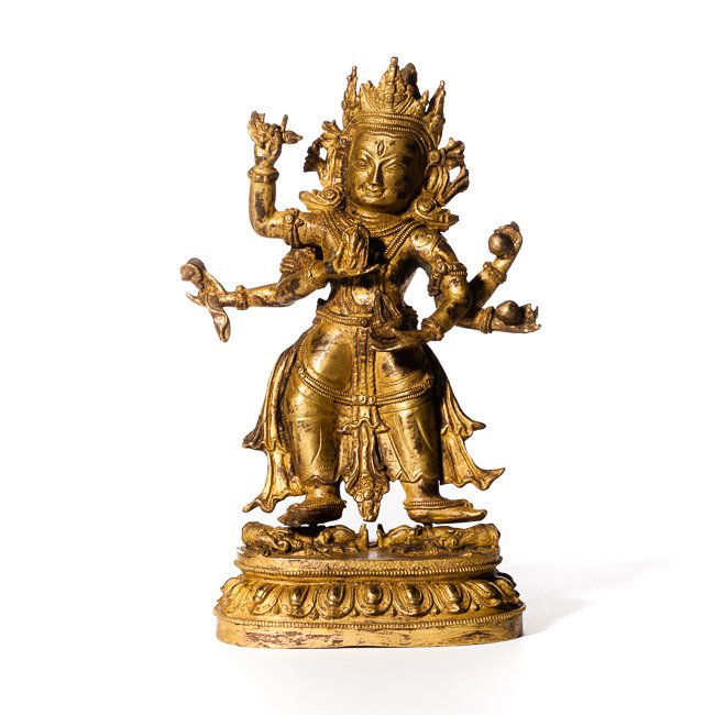 19th Chinese Antique Standing Gilt Bronze Buddha Figure: The God of Pristine Awareness, a wrathful emanation of Avalokitesvara, standing on the corpse of the elephant-headed Ganapati, cast with six hands and three eyes, the central hands holding a curved kn