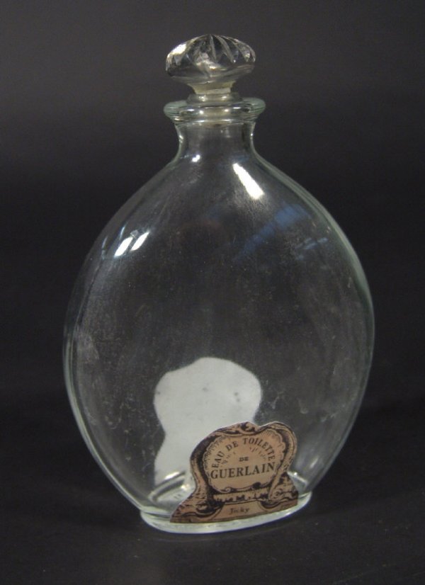 Guerlain oval glass scent bottle and stopper with: Guerlain oval glass scent bottle and stopper with paper label for 'Jicky Eau De Toilette', moulded factory mark to the base, 14cm high