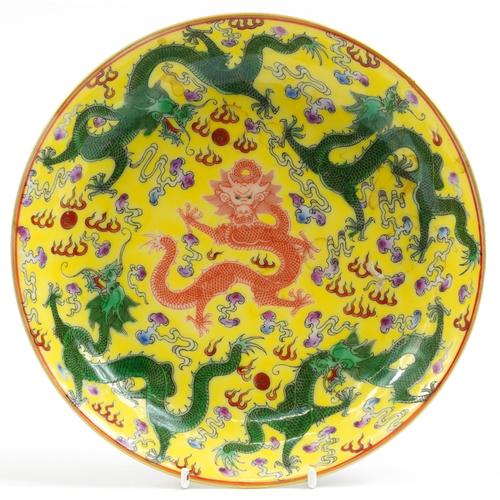 Chinese porcelain yellow ground dish hand painted with dragons chasing the flaming pearl, six figure: Chinese porcelain yellow ground dish hand painted with dragons chasing the flaming pearl, six figure character marks to the reverse, 21cm in diameter