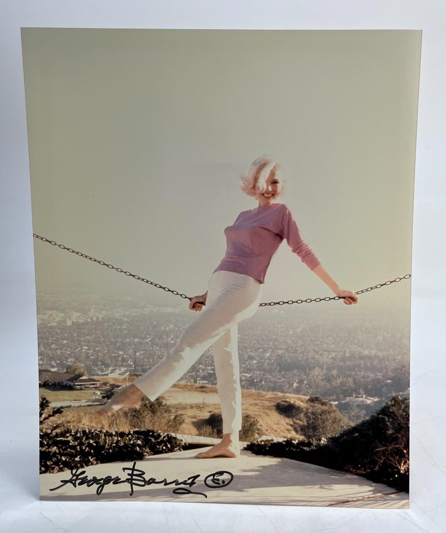 Marilyn Monroe Photograph George Barris: A limited edition George Barris photograph of Marilyn Monroe, depicting Marilyn Monroe posing while leaning on chain. Signed by George Barris in marker (lower left). Stamped and numbered 22/40 on reve