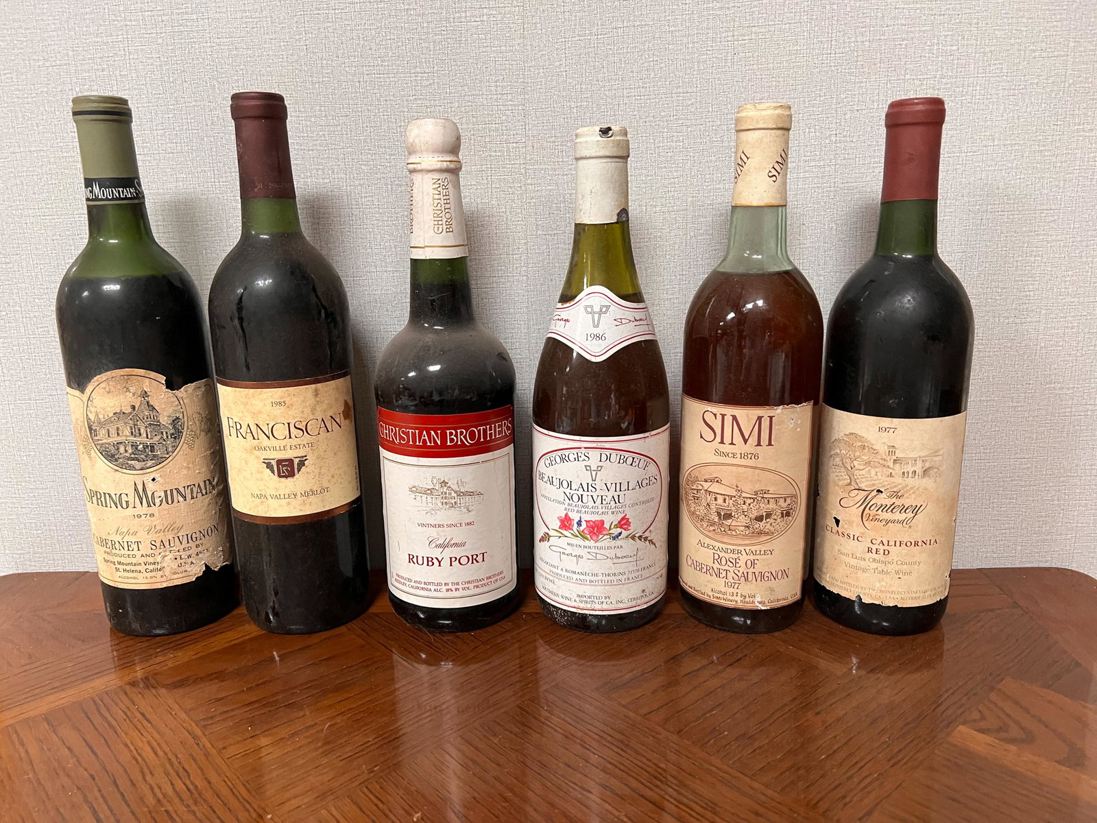 6 Vintage Estate Bottles of Wine Spirits Assorted: Spring Mountain Cabernet Sauvignon 1978; Oakville Estate Franciscan 1985; Christian Brothers Ruby Port; Georges Duboeuf 1986; Alexander Valley Simi 1977; The Monterey Vinyard Red 1977 Domestic Shippin