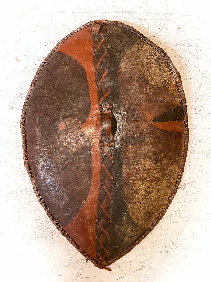 Massai Kenya Tanzania Leather Shield: Buffalo hide stretched to an oval form, bent wood handle on reverse. Approx 7lbs Approx measurements 36.5 x 24.125 x 4.5 inches