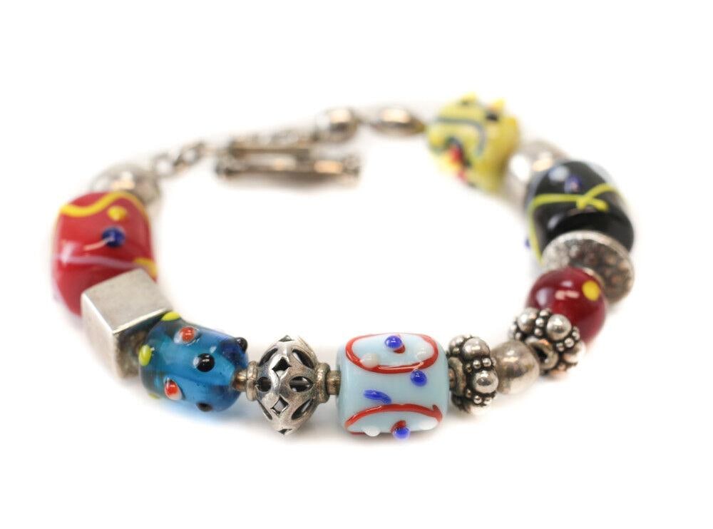 Silpada Sterling Silver Glass Bracelet sterling and multicolored glass charms: Desciption: Vintage Silpada Sterling Silver Glass Bracelet, sterling and multicolored glass charms, toggle closure. Makers mark. 38.8grams Measurements: Approx., 7.75inches length Domestic Shipping: $