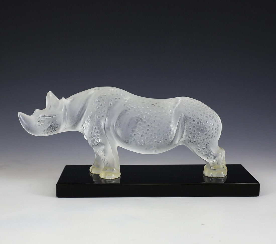 Lalique Art Glass Rhinoceros TOBA Figurine, acid etched, on black glass plinth.: Lalique Art Glass Rhinoceros TOBA Figurine, acid etched, on black glass plinth. Marked 'Lalique France' on base. Weight 7.25lbs Approx. Measurements: 9.675" x 4" at base, rhino 10.25" length x 4.5" he