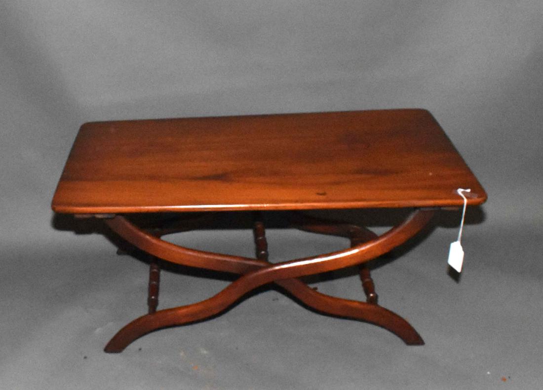 A MAHOGANY FOLDING LOW TABLE WITH CURULE-FORM BASE AND: A MAHOGANY FOLDING LOW TABLE WITH CURULE-FORM BASE AND RECTANGULAR TOP. 17 1/2 in. high; 39 in. wide; 22 in. deep.
