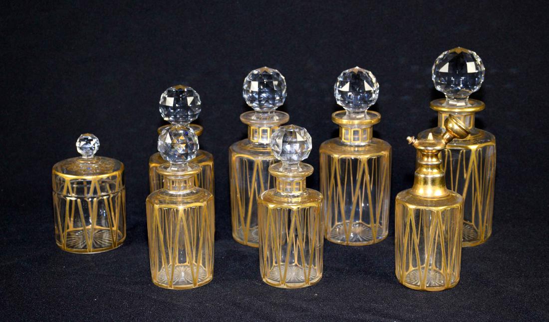 A SET OF COLORLESS GLASS LADIES' DRESSING TABLE BOTTLES: A SET OF COLORLESS GLASS LADIES' DRESSING TABLE BOTTLES AND JARS, all with gilt decoration, probably French.