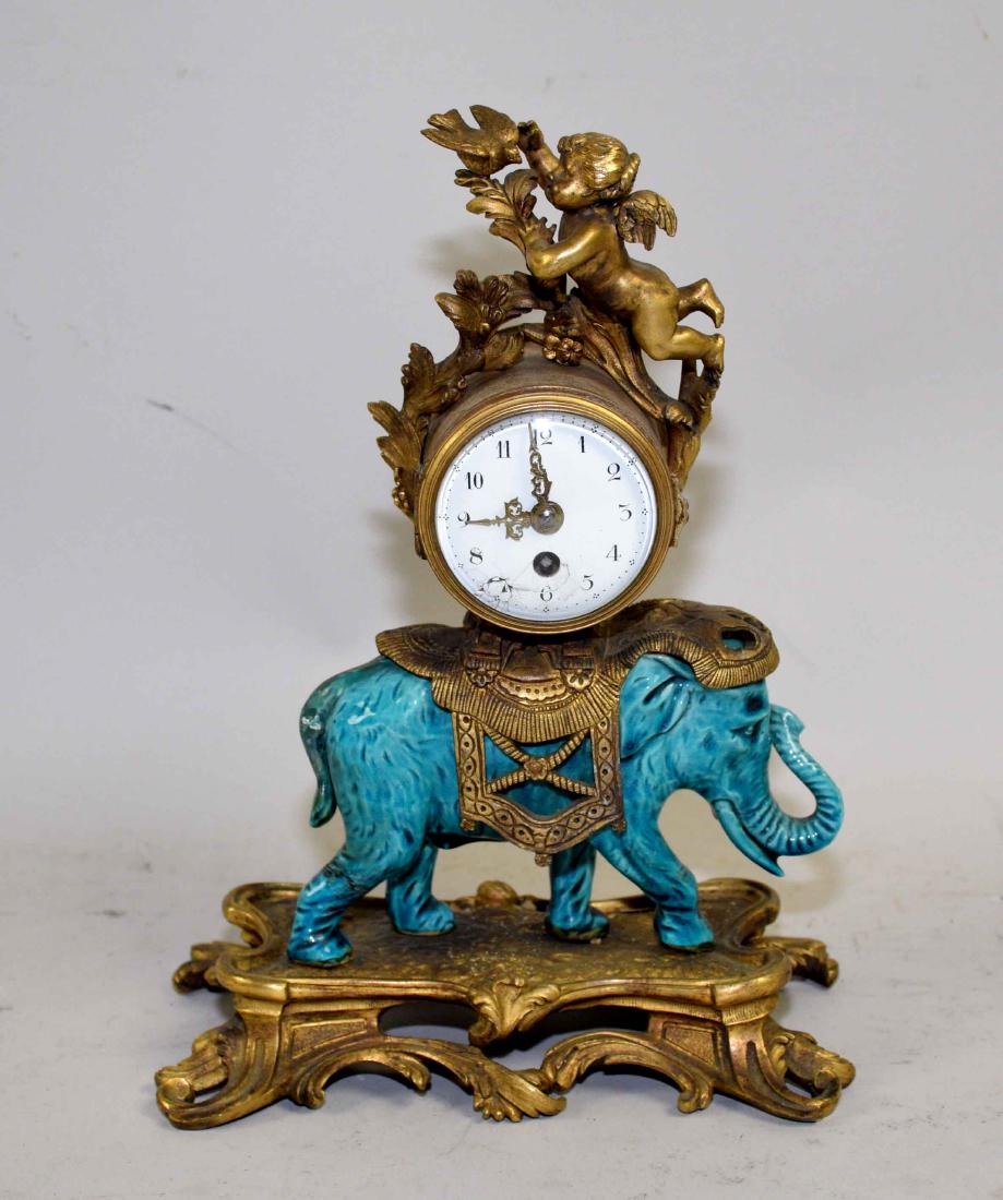 A RESTAURATION STYLE BRONZE AND PORCELAIN ''ELEPHANT'': A RESTAURATION STYLE BRONZE AND PORCELAIN ''ELEPHANT'' TABLE CLOCK. Late 19th Century. The dome clock enameled with Arabic numerals within a putto surmount, mounted on a Chinese turquoise-glazed porce