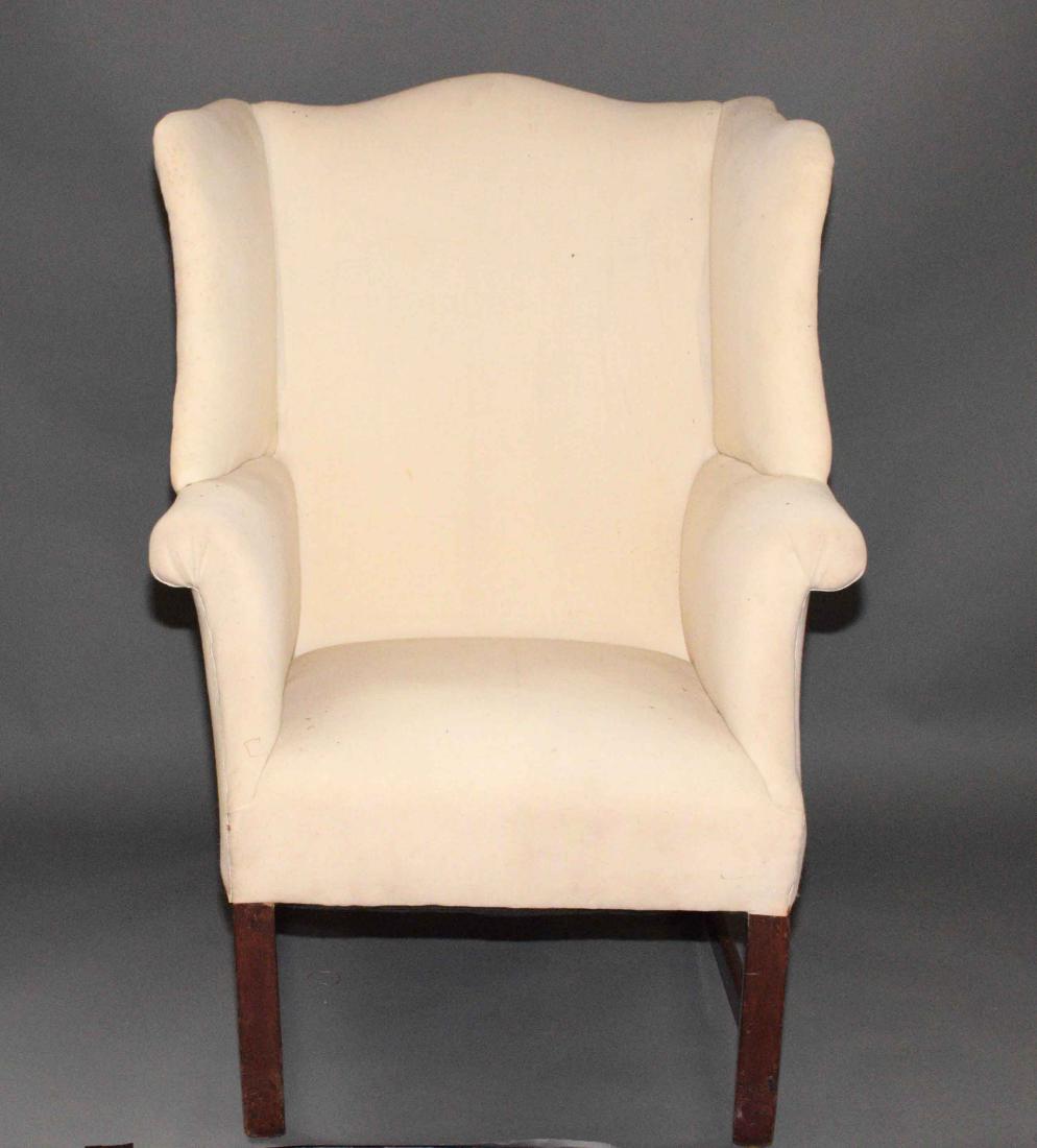 A GEORGE III MAHOGANY WING-BACK ARMCHAIR. Late 18th: A GEORGE III MAHOGANY WING-BACK ARMCHAIR. Late 18th Century. With wide saddle sides, rolled arms and seat covered in ivory muslin; on plain square legs joined by a three-quarter box stretcher. 39 in h