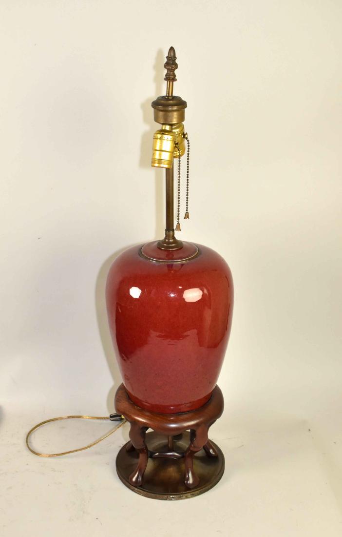 A CHINESE OXBLOOD-GLAZED OVIFORM JAR AND COVER, mounted: A CHINESE OXBLOOD-GLAZED OVIFORM JAR AND COVER, mounted as a lamp. The jar 18th/19th Century. On a cabriole leg footed mahogany base with metal foot, drilled. 11 in. high; 9 1/2 in. wide.