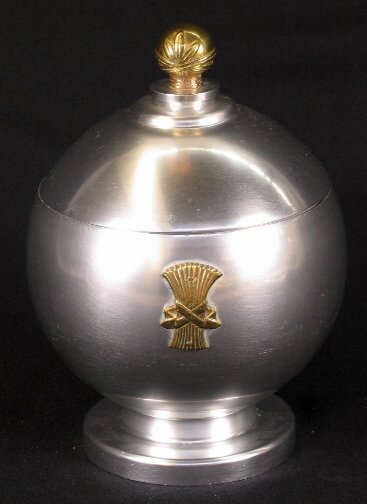 KENSINGTON WARE SPHERE JAR. 1934-1935. Brass and: KENSINGTON WARE SPHERE JAR. 1934-1935. Brass and spun aluminum sphere jar designed by Lurelle Guild in 1934. Footed and lidded jar with brass wheat sheaf decoration and brass ball finial. Cat. No. 747