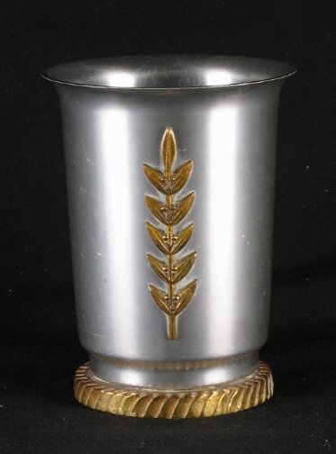 KENSINGTON WARE LAUREL VASE 7''. 1934-1935. Art D: KENSINGTON WARE LAUREL VASE 7''. 1934-1935. Art Deco aluminum and brass ''Laurel Vase'' cat. no. 7027. Designed by Lurelle Guild. Brass laurel branch decoration, solid brass base. Early mark. Marked: