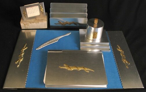 KENSINGTON WAVERLY DESK SET. c. 1934-35. Lot incl: KENSINGTON WAVERLY DESK SET. c. 1934-35. Lot includes six pieces. Designed by Lurelle Guild. Aluminum and brass decoration. All are marked: stag head, shield and script mark. 1. Waverly Blotter Holder
