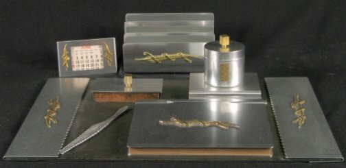 KENSINGTON WAVERLY DESK SET. c. 1934-35. Lot incl: KENSINGTON WAVERLY DESK SET. c. 1934-35. Lot includes seven pieces. Designed by Lurelle Guild. Aluminum and brass decoration. All are marked: stag head, shield and script mark. 1. Waverly Blotter hold