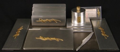 KENSINGTON WAVERLY DESK SET. c. 1934-35. Lot incl: KENSINGTON WAVERLY DESK SET. c. 1934-35. Lot includes six pieces. Designed by Lurelle guild. Aluminum and brass decoration. All are marked: stag head, shield and script mark. 1. Waverly Blotter Holder