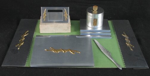KENSINGTON WAVERLY DESK SET. c. 1934-35. Lot incl: KENSINGTON WAVERLY DESK SET. c. 1934-35. Lot includes five pieces. Designed by Lurelle Guild. Aluminum and brass decoration. All are marked: stag head, shield and script mark. 1. Waverly Blotter Holde