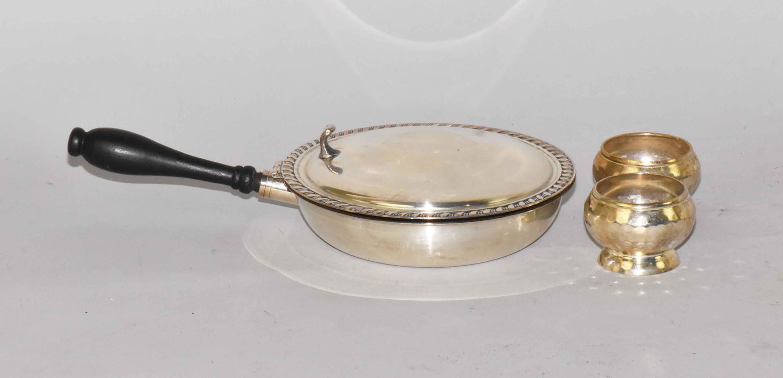 (2) HAND HAMMERED DESIGN SALTS AND AN ANTIQUE SILVER ON: (2) HAND HAMMERED DESIGN SALTS AND AN ANTIQUE SILVER ON COPPER LIDDED WARMING DISH W/WOOD HANDLE. W/crown, S & Shield stamp. 2.5''H x 7'' diameter. Estate of Stephen Totter.