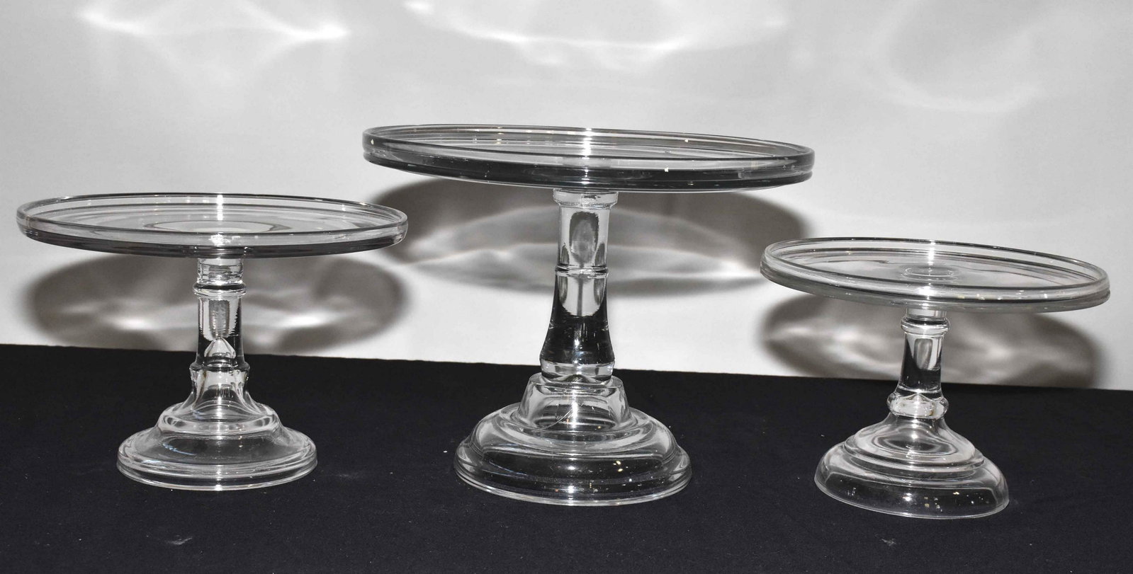 COLLECTION OF (3) GLASS CAKE STANDS. Largest: 9.5''H x: COLLECTION OF (3) GLASS CAKE STANDS. Largest: 9.5''H x 12.5'' diameter.
