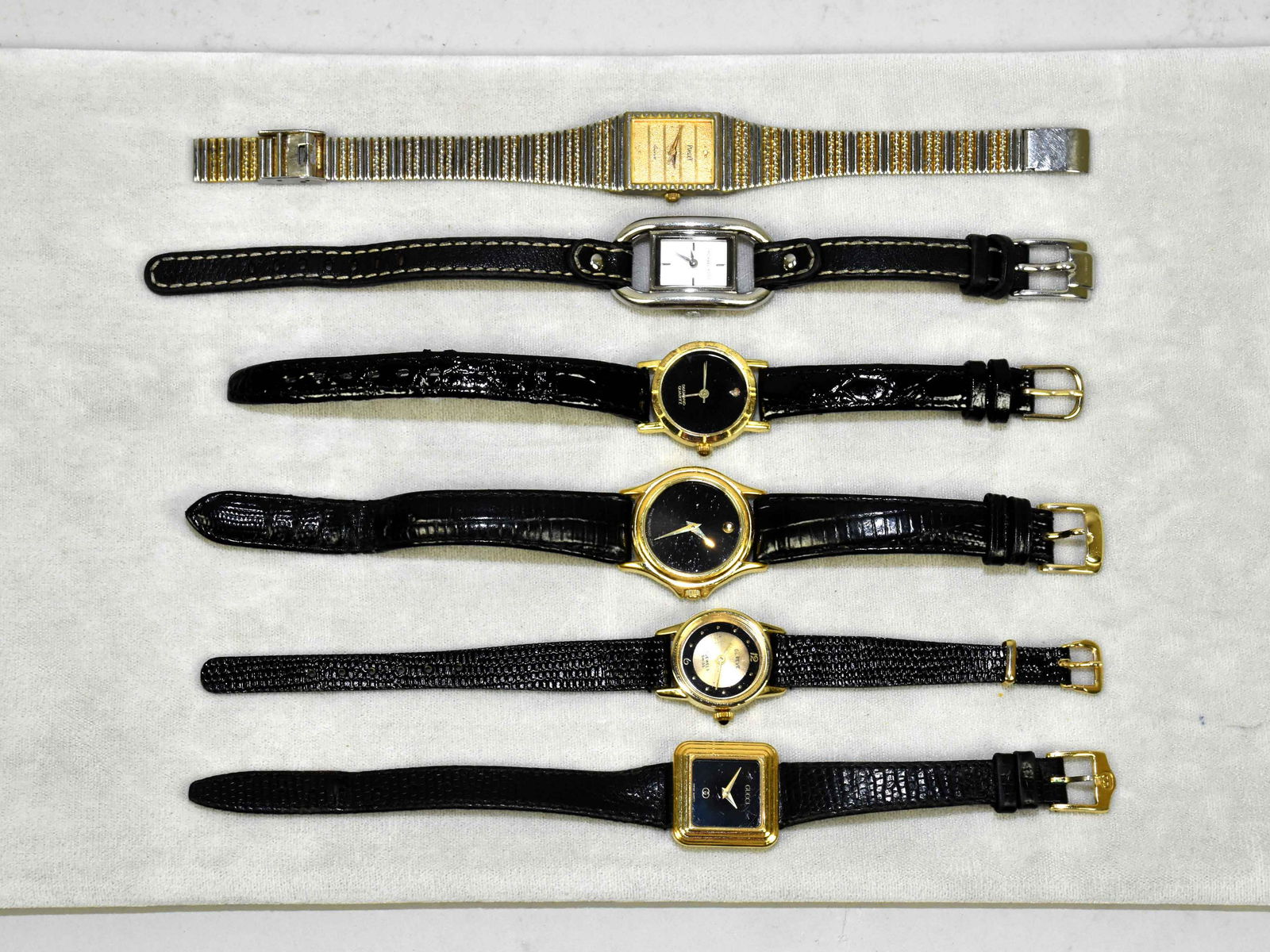 (6) ASST. LADIES QUARTZ WRISTWATCHES. To include: (3): (6) ASST. LADIES QUARTZ WRISTWATCHES. To include: (3) Swiss movement; Geneve, Gucci and Movado. (1) Japanese, 1 M. Kors, all with black leather strap. Piaget, stainless steel. In gold and silver tones