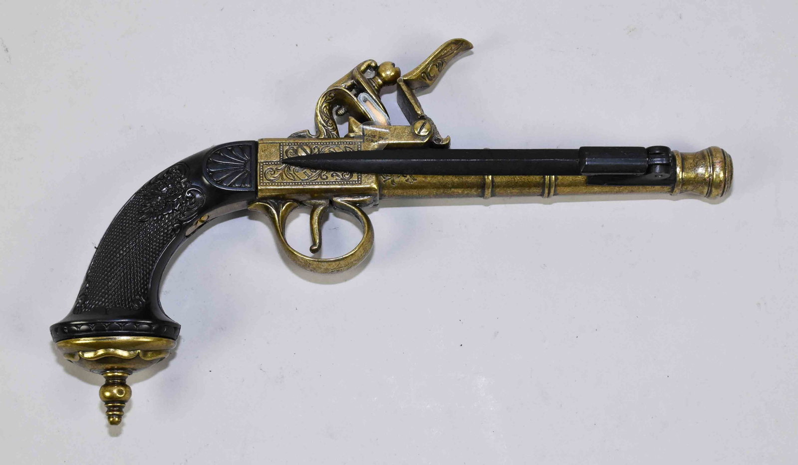 REPLICA ENGLISH FLINTCOCK PISTOL - Gold colored metal: REPLICA ENGLISH FLINTCOCK PISTOL - Gold colored metal with black resin grip and folding side bayonet.