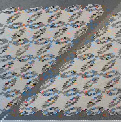 INTERLOCKING RING QUILT: INTERLOCKING RING QUILT. 20th c. Hand made interlocking ring pattern (wedding ring) quilt, interlocking rings of multicolored pieces with blue predominating on white ground, with white back. No mark.