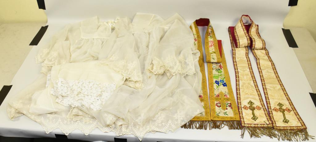 (FIVE) VINTAGE PRIESTS ITEMS. (THREE) SURPLICES: (FIVE) VINTAGE PRIESTS ITEMS. (THREE) SURPLICES SIZE L – XL WITH HEAVY LACE EMBROIDERY, SOME STAINING ON ONE. (TWO) VINTAGE STOLES WITH SATIN TAPESTRY MATERIAL, METAL EMBROIDERY AND FRINGE.