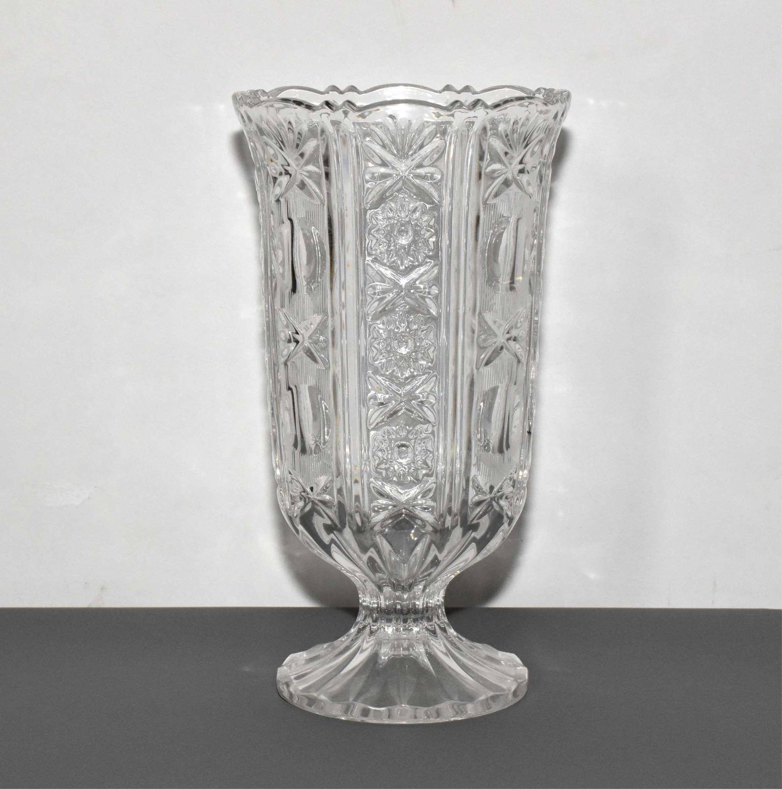 PRESSED CRYSTAL VASE: PRESSED CRYSTAL VASE - Alternating panels of stripes, thumbÂ­prints and bows and floral sprays and bows. 9.75" high.