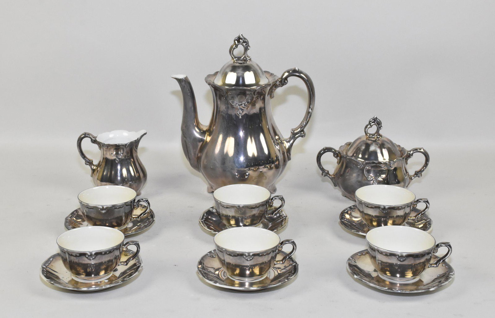 SILVER DEPOSIT PORCELAIN DEMITASSE SERVICE FOR: SILVER DEPOSIT PORCELAIN DEMITASSE SERVICE FOR SIX - Arboise Co. Complete with pot, sugar, cream, and six cups and saucers.