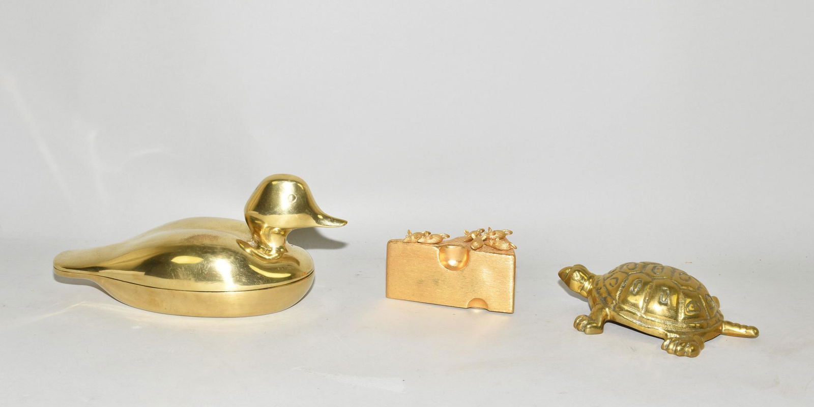 THREE BRASS DECORATIVE OBJECTS - Heavyweight cast: THREE BRASS DECORATIVE OBJECTS - Heavyweight cast brass duck box (Avon), solid brass turtle figure, gilt slice of Swiss cheese with six small mice attached in the form of cheese picks.