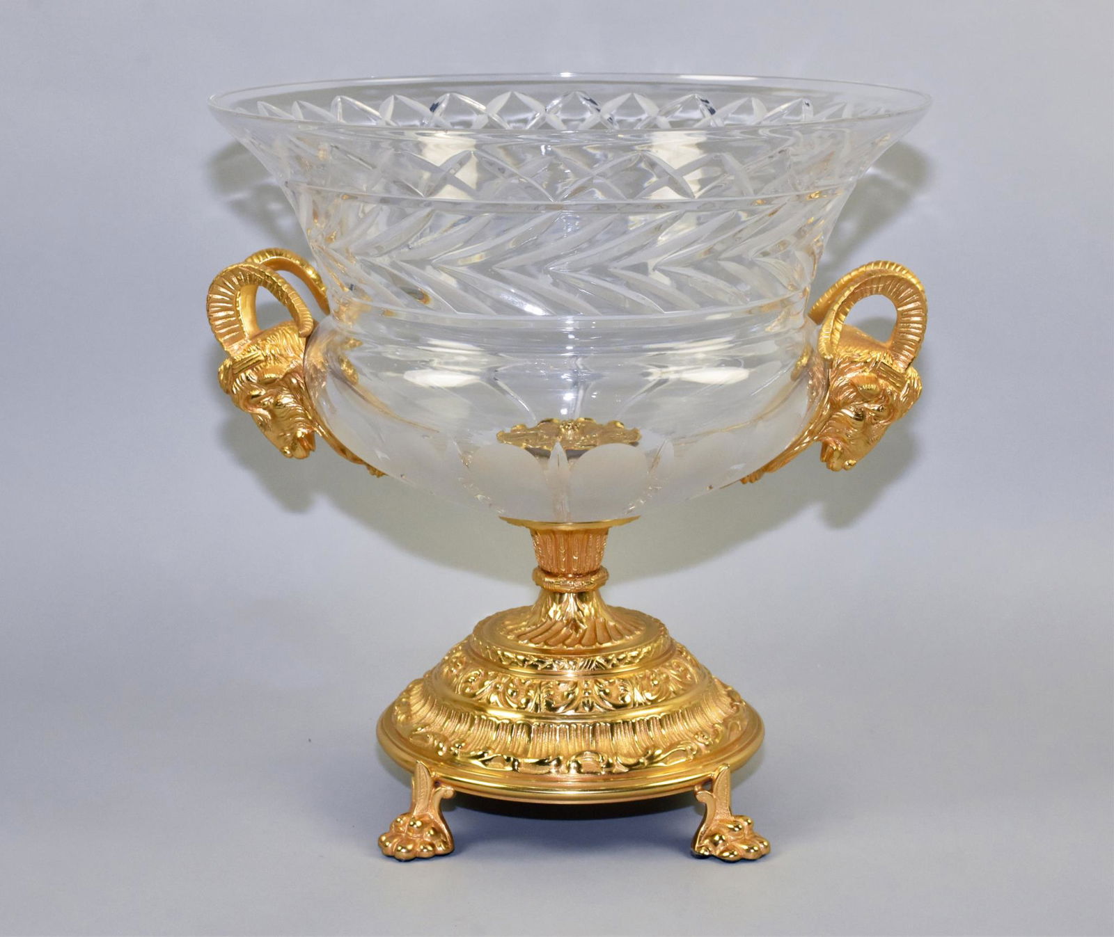 ENGRAVED CRYSTAL CENTERPIECE: ENGRAVED CRYSTAL CENTERPIECE. Rams head gold gilt handles. Purchased at David Michael's. Dimensions: 15" h x 14.5" diameter at top. 16" wide with Rams head accents.