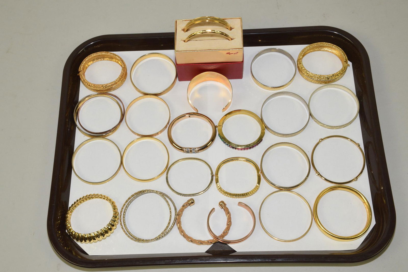20 GOLDTONE FASHION BANGLES, A VARIETY OF STYLES: 20 GOLDTONE FASHION BANGLES, A VARIETY OF STYLES. Designer signed: Milar Italy, Michael Kors, Givenchy and Monet.