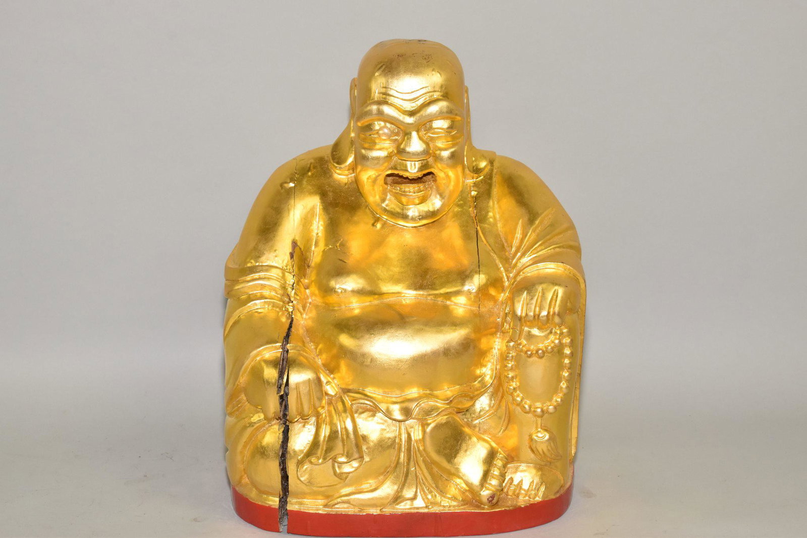 HOTEi - CARVED AND HEAVILY GILDED WOOD FIGURE OF: HOTEi - CARVED AND HEAVILY GILDED WOOD FIGURE OF THE IMMORTAL REPRESENTING _ __ __ 14" h. x 10" w x 7" deep. Well executed figure of the jolly fat man clutching a string of beads in his left hand. Not
