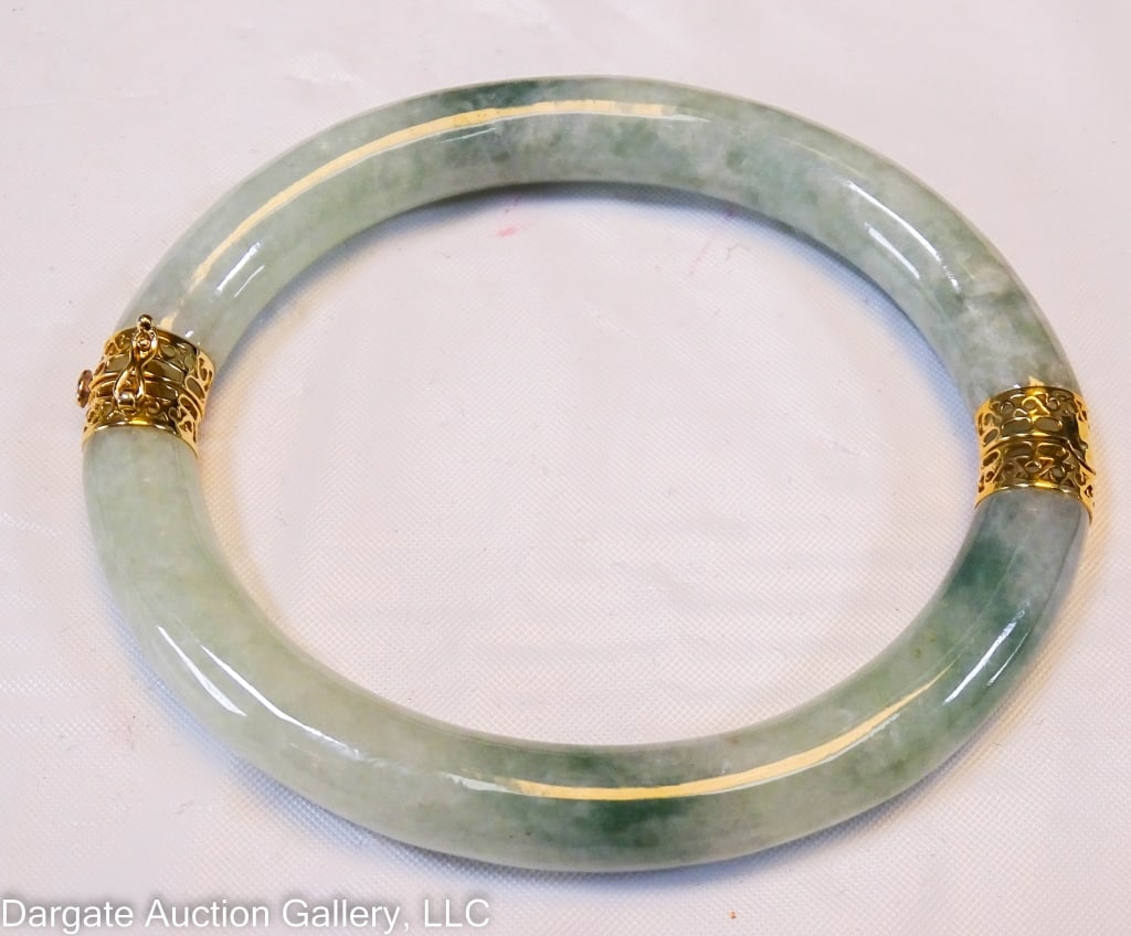 14K GOLD AND JADE BRACELET: Oval shaped jade bracelet with 14k yellow gold caps, with safety catch on clasp. / Weight: Total weight: 44.85g / Measurements: 3"w x 2.75"W / Provenance: From the descendants of Lollie Oliver, Pittsu