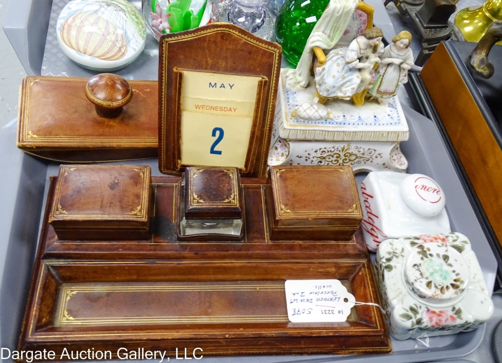 LEATHER DESK SET w/ PORCELAIN INKWELLS: A leather desk set with porcelain inkwells. Leather desk set with gold trim. One porcelain inkwell young girls and their dog on the lid. Another with a Chinese mark. / Measures: Inkwell pen holder: 11