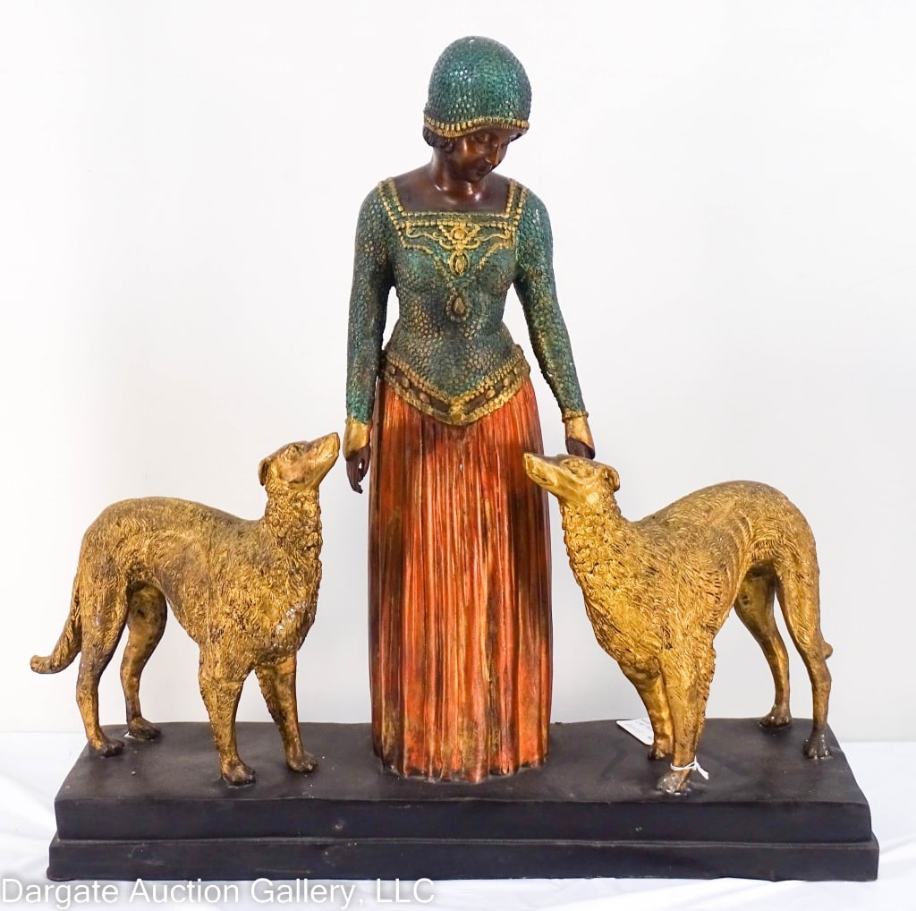 ART DECO BRONZE SCULPTURE OF LADY AND DOGS: A 20th century Art Deco bronze sculpture of a lady & her dogs after artist Demetre Chiparus, 1886-1947, Romania. Cold-painted bronze hollow base. / Measures: 22"Hx5.75"Wx22"D / Provenance: From the de
